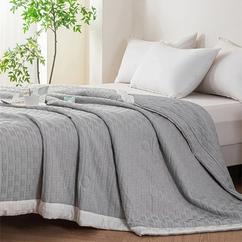 DecorBites Knitted Waffle Summer Quilt gray with weave on a bed with white pillows on Tampa Home & Garden Store