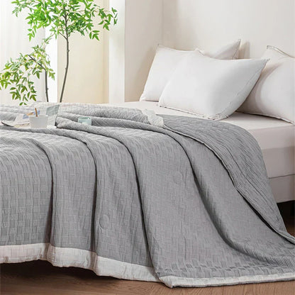 DecorBites Knitted Waffle Summer Quilt gray with weave on a bed with white pillows on Tampa Home & Garden Store