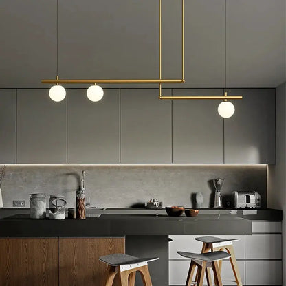 DecorBites linear minimalist chandelier pendant light in brass with globe bulbs over island on Tampa Home & Garden Store