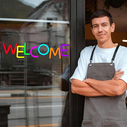 Welcome neon sign with multicolor letters on glass storefront; man in gray apron beside the door on Tampa Home & Garden Store