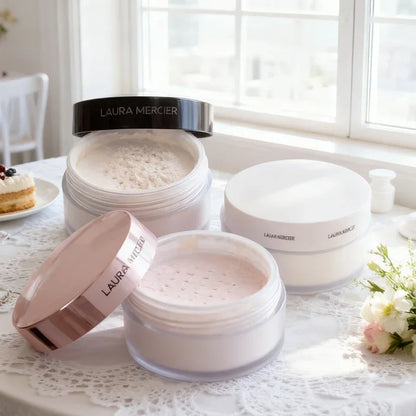 Laura Mercier translucent loose powder jars with white and pink lids on lace table by window on Tampa Home & Garden Store