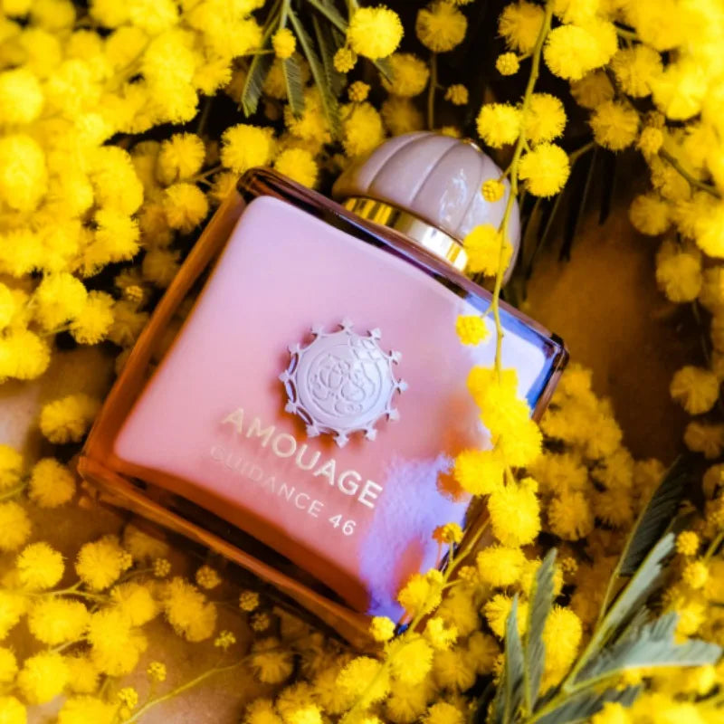 AMOUAGE Guidance 46 perfume bottle pink glass with gold cap amid yellow mimosa blooms on Tampa Home & Garden Store