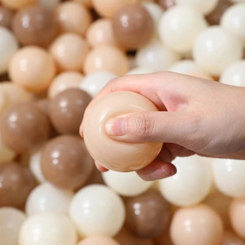 Tiny Land Ocean Ball ball pit ball in assorted beige tan and white colors held in hand on Tampa Home & Garden Store