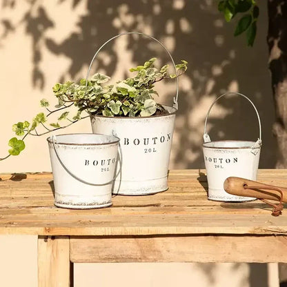 White farmhouse bucket planters set of 3, distressed metal with handles and trailing greenery on Tampa Home & Garden Store
