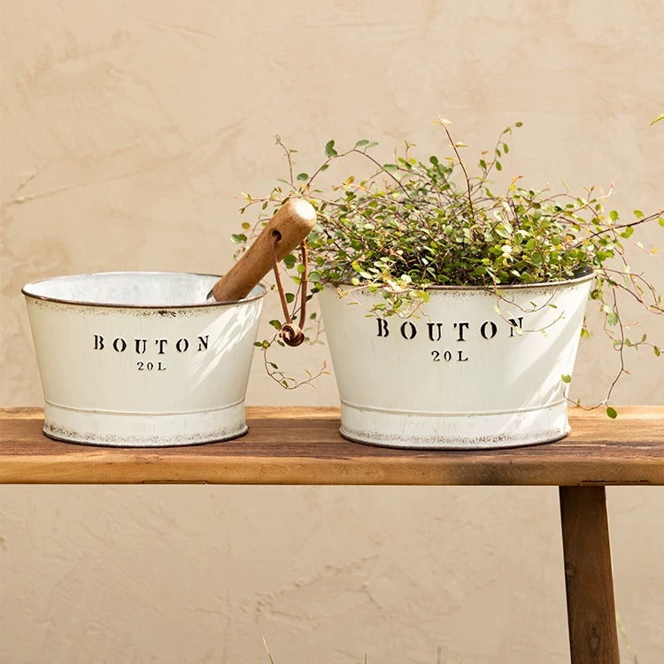 Two white vintage trough metal planters with distressed rims on a wooden table on Tampa Home & Garden Store