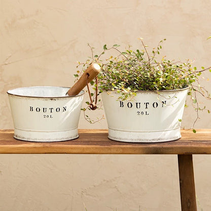 Two white vintage trough metal planters with distressed rims on a wooden table on Tampa Home & Garden Store