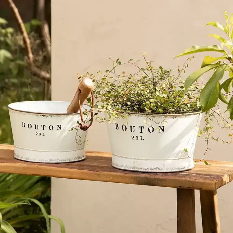 White vintage trough metal planters, two with Bouton 20L lettering; one has a wooden handle on Tampa Home & Garden Store
