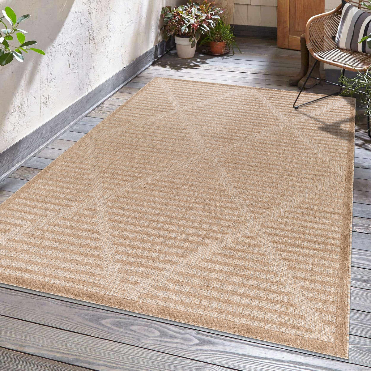 Anah Tan Outdoor Rug on a wooden deck with natural woven texture and potted plants on Tampa Home & Garden Store