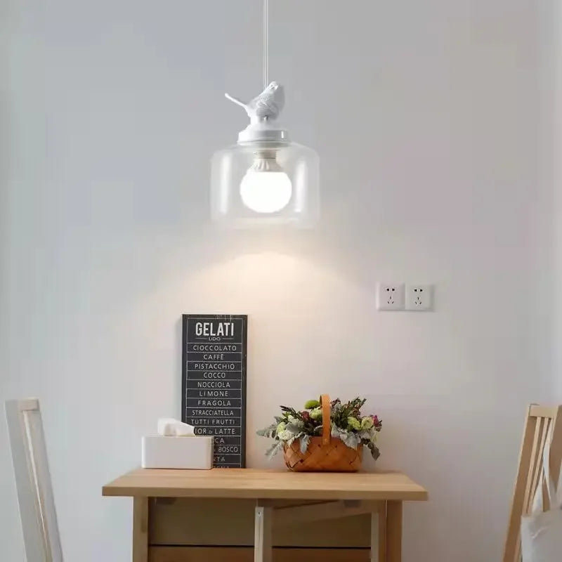 Birds glass pendant light with clear jar shade and white bird topper over a dining table on Tampa Home & Garden Store