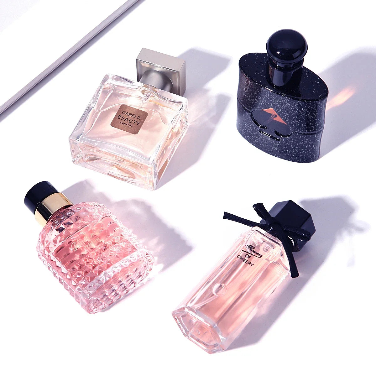 Four-piece perfume set with pink textured bottle, clear square bottle, ribbon-tied pink bottle, and navy speckled bottle on Tampa Home & Garden Store
