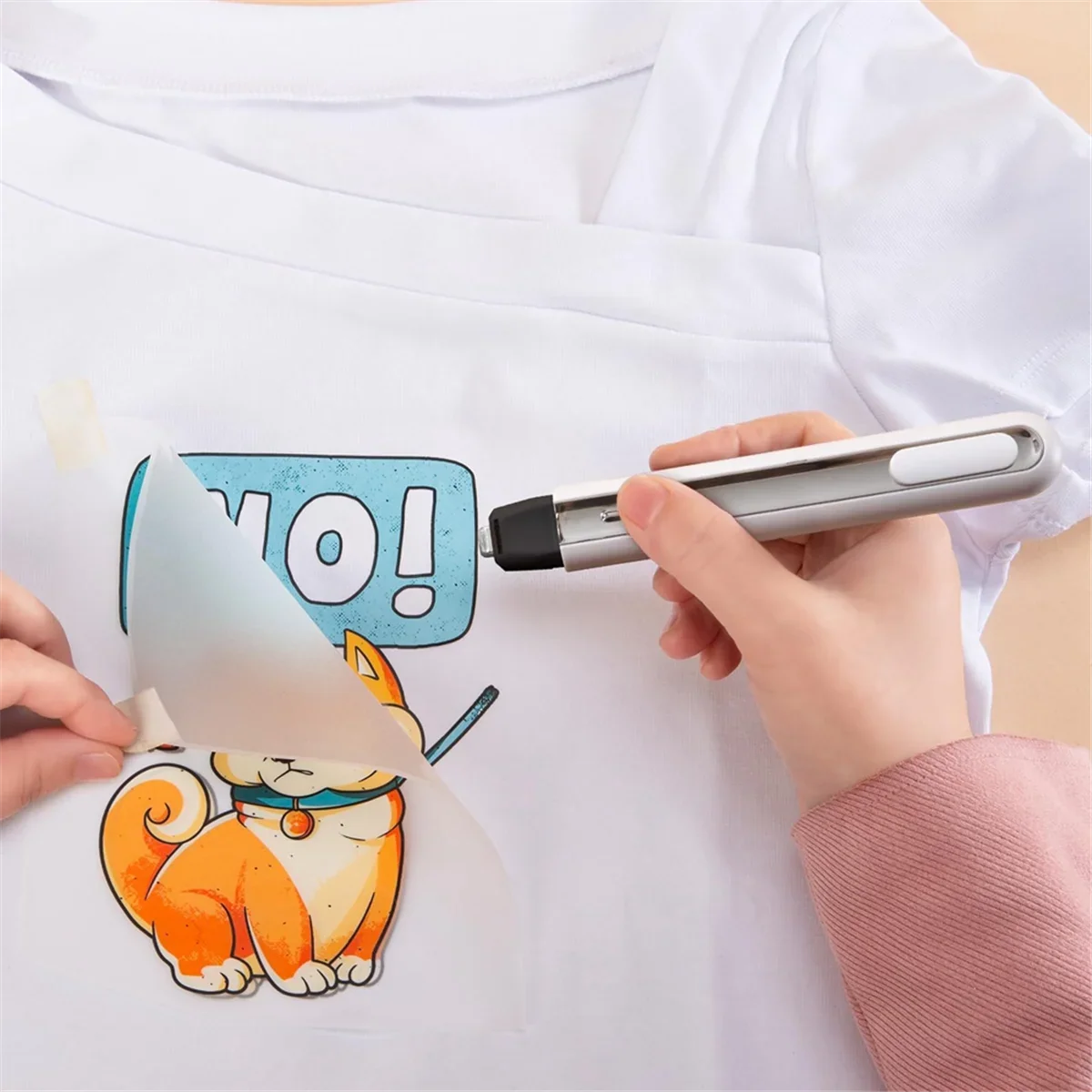 Cordless mini heat press in silver/black applying orange cat graphic with blue NO on white shirt on Tampa Home & Garden Store