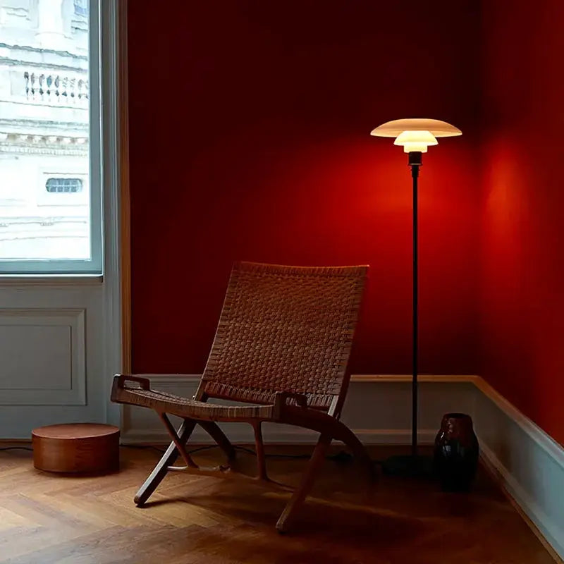 LED Floor Lamp with black stem and offwhite mushroom shade beside a wicker chair in red room on Tampa Home & Garden Store