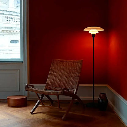 LED Floor Lamp with black stem and offwhite mushroom shade beside a wicker chair in red room on Tampa Home & Garden Store
