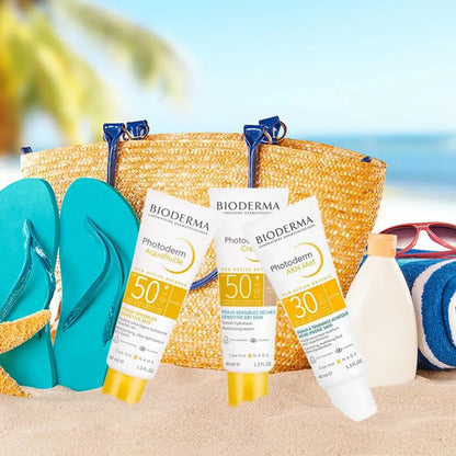 BIODERMA Photoderm sunscreen SPF50+ and SPF30 on a beach with a straw tote and flip-flops on Tampa Home & Garden Store