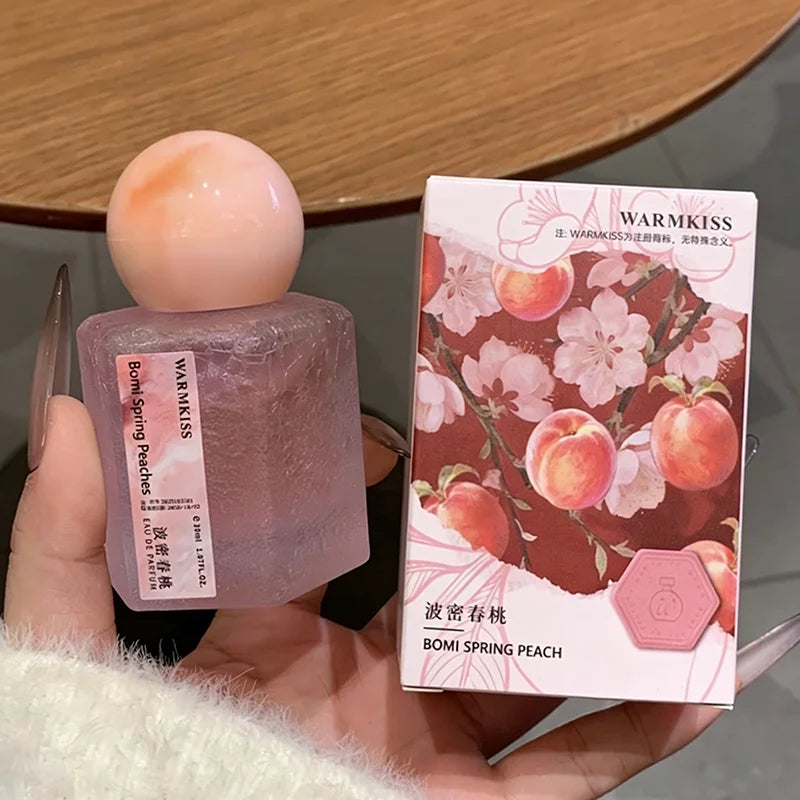 Silcy Skin rose perfume bottle with frosted glass and peach cap beside a peach blossom box on Tampa Home & Garden Store