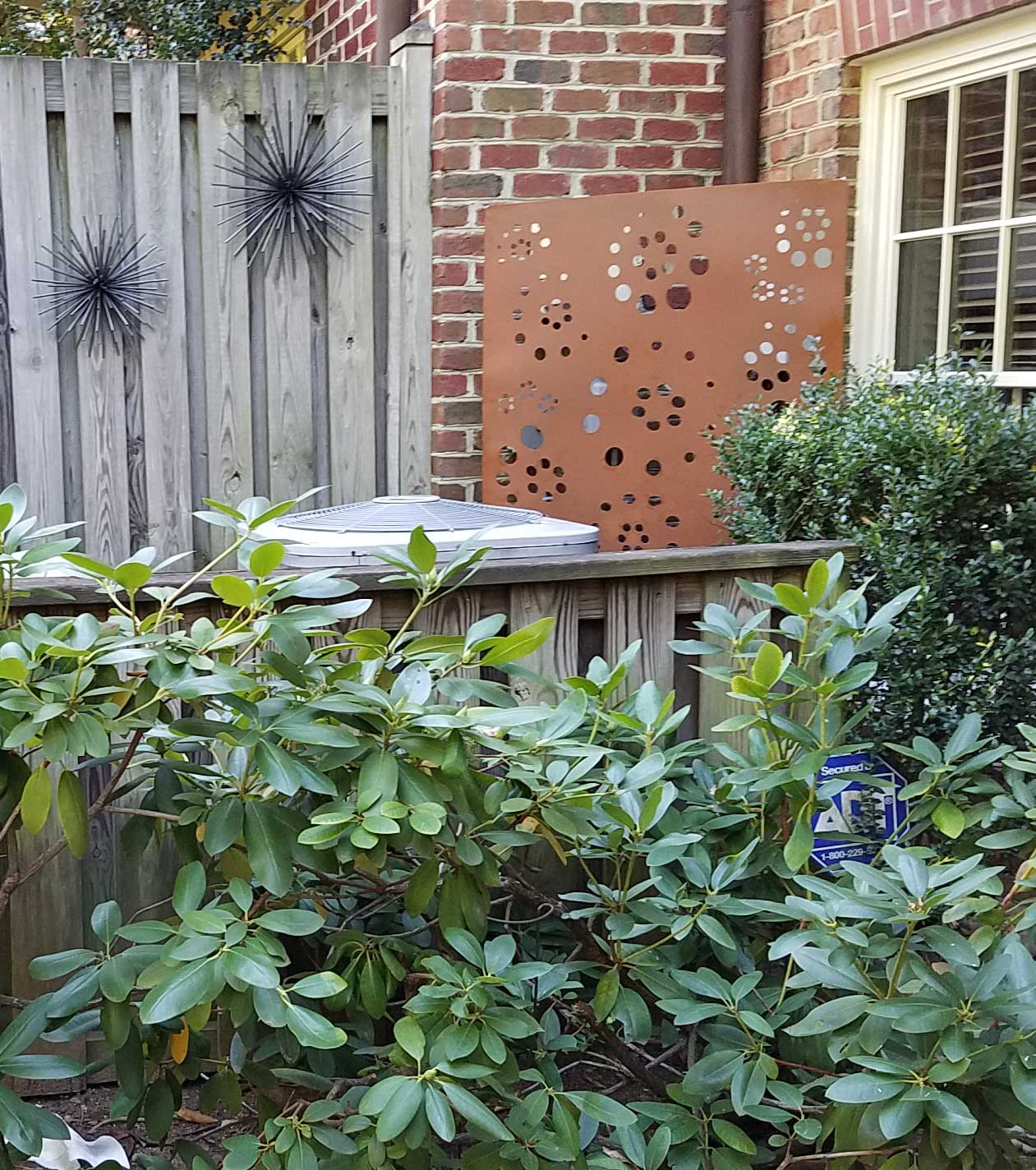 Rustica Ornamentals metal privacy screen copper panel and two black starburst sculptures on fence on Tampa Home & Garden Store