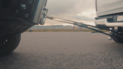 Lightweight Ridge Belt tow strap system between two pickups on a highway at sunset on Tampa Home & Garden Store