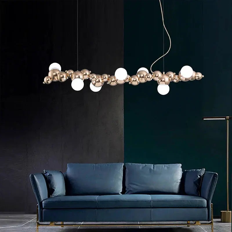 DecorBites LED pendant chandelier with rose-gold spheres and white globes over a blue sofa on Tampa Home & Garden Store