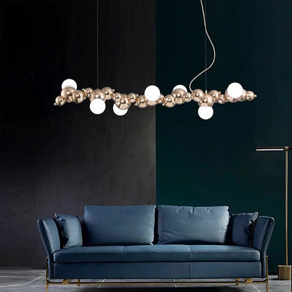 DecorBites LED pendant chandelier with rose-gold spheres and white globes over a blue sofa on Tampa Home & Garden Store