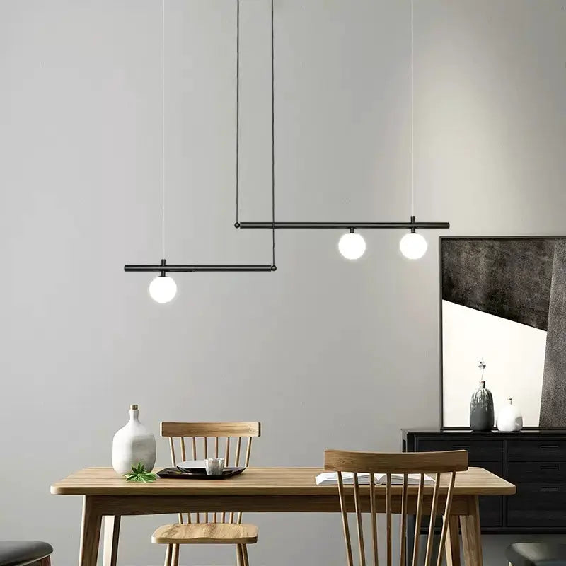 DecorBites Linear Pendant Light in black metal with globe bulbs over a wooden dining table on Tampa Home & Garden Store