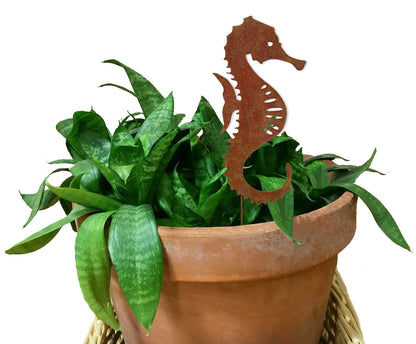 Seahorse plant stake by Rustica Ornamentals in rust finish among leaves in terracotta pot on Tampa Home & Garden Store