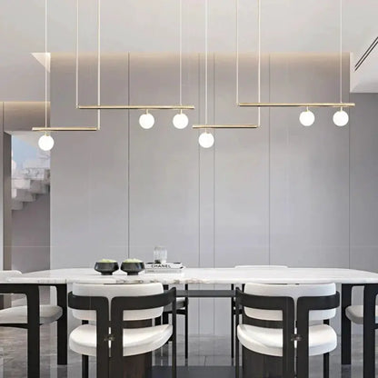 Decorbites linear chandelier with gold bars and white globes over dining table on Tampa Home & Garden Store