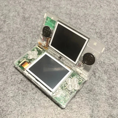 Clear plastic handheld game console shell with dual screens, exposed PCB and round speakers on Tampa Home & Garden Store