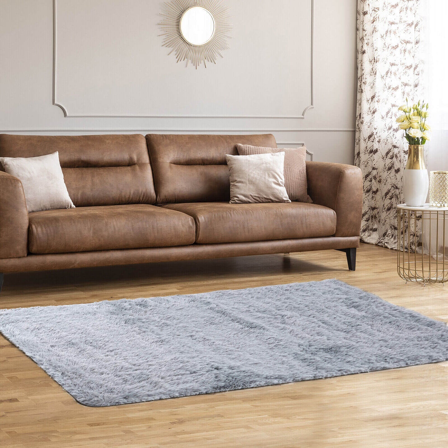 Brown leather sofa with beige pillows in a living room with a sunburst mirror on Tampa Home & Garden Store