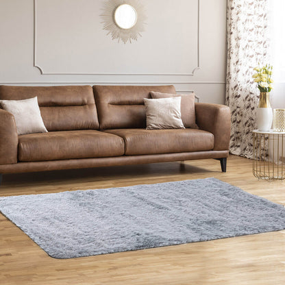 Brown leather sofa with beige pillows in a living room with a sunburst mirror on Tampa Home & Garden Store