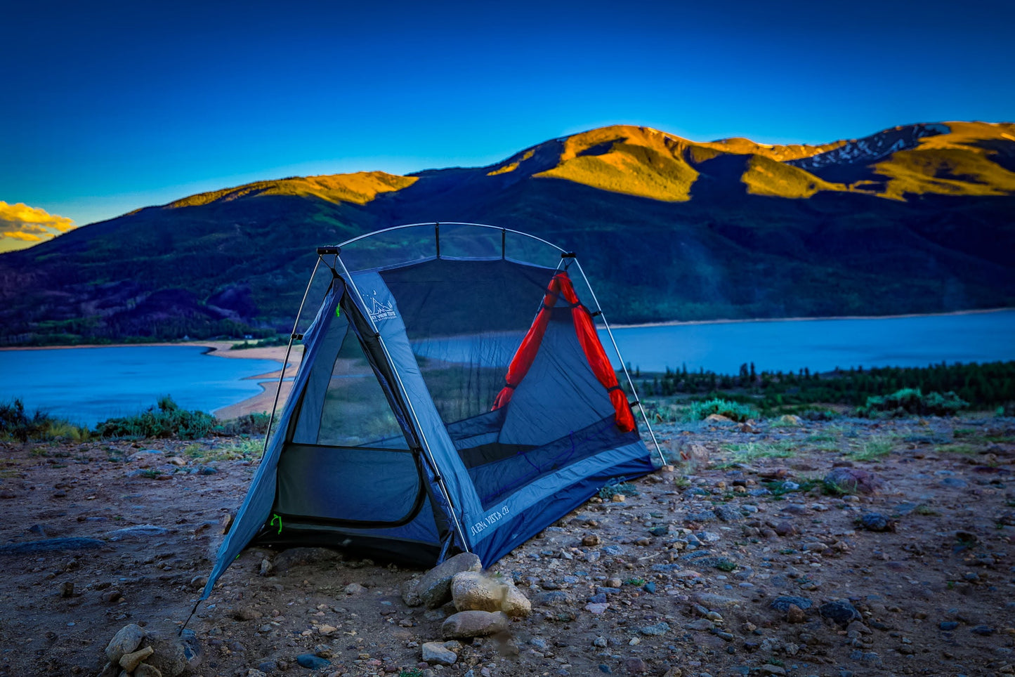 Sky View Solo Tent, blue-gray single-person tent with red rainfly beside a lake at sunset on Tampa Home & Garden Store