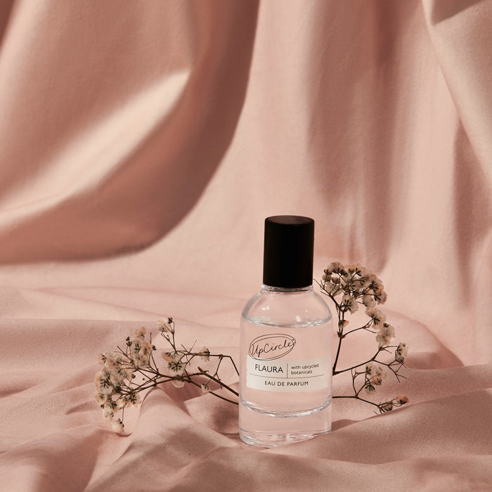 Flaura Eau De Parfum by UpCircle; clear bottle with black cap on pink fabric backdrop on Tampa Home & Garden Store