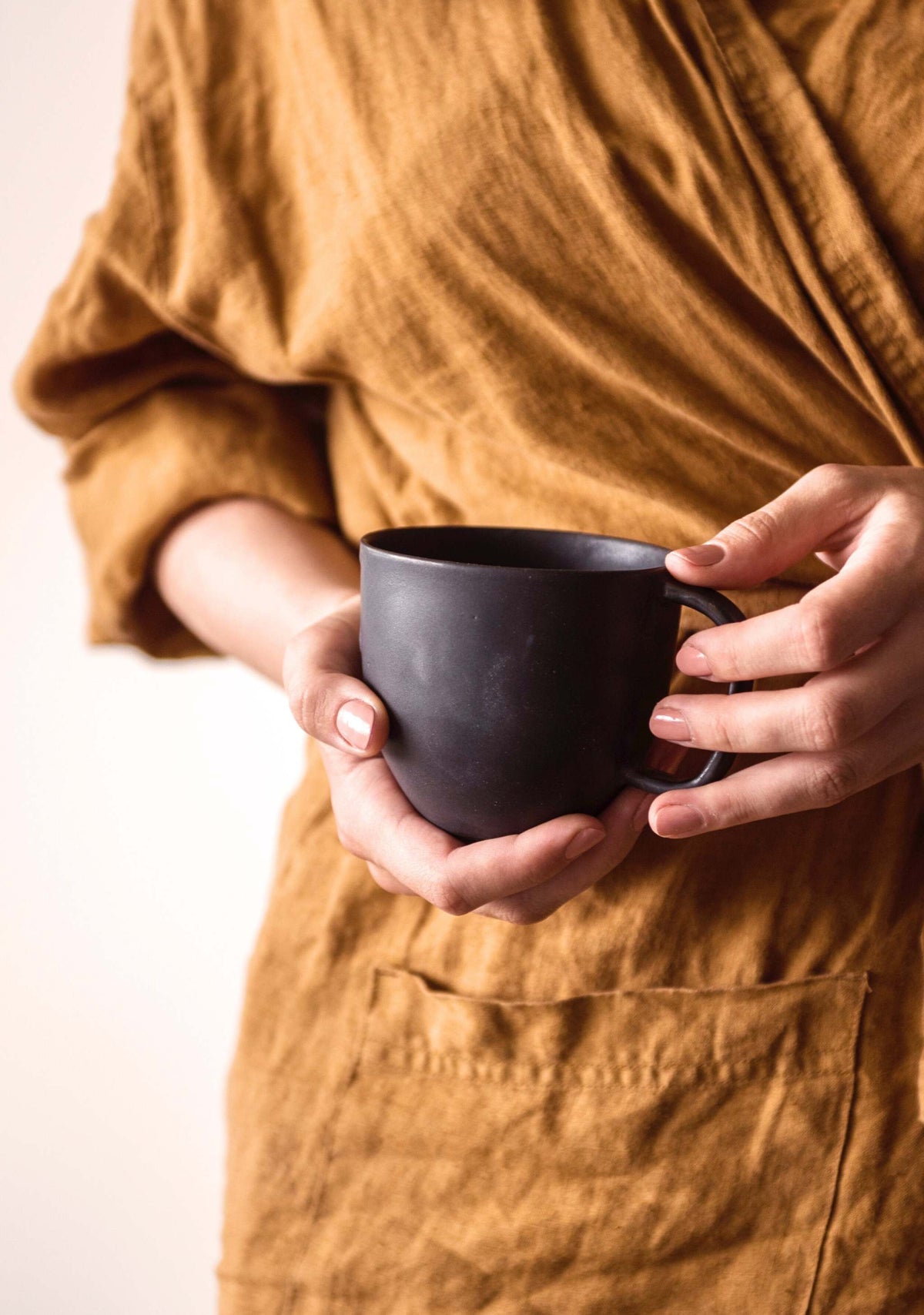 Black matte stoneware mug by Creating Comfort held in hands on Tampa Home & Garden Store