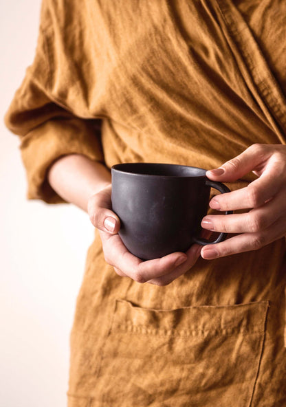 Black matte stoneware mug by Creating Comfort held in hands on Tampa Home & Garden Store