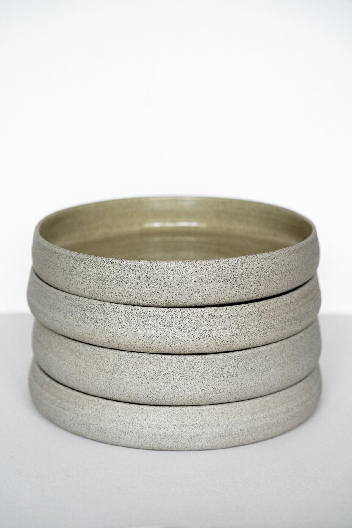 Handmade stoneware dinner plates with high sides in concrete gray, stacked by Creating Comfort on Tampa Home & Garden Store