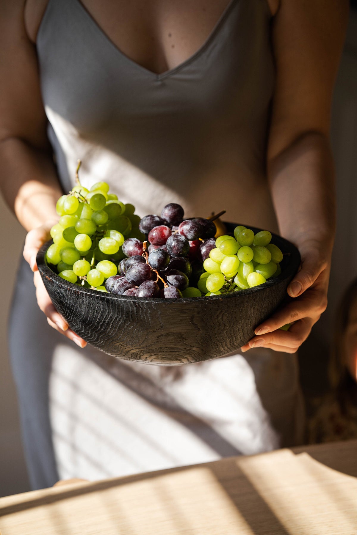 Hand-Carved Large Charred Black Wood Bowl filled with green and purple grapes, held by a person on Tampa Home & Garden Store