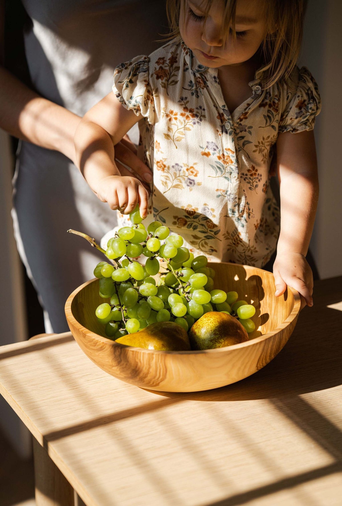 Hand carved wooden nesting bowl set in light wood holds green grapes and pears on table on Tampa Home & Garden Store