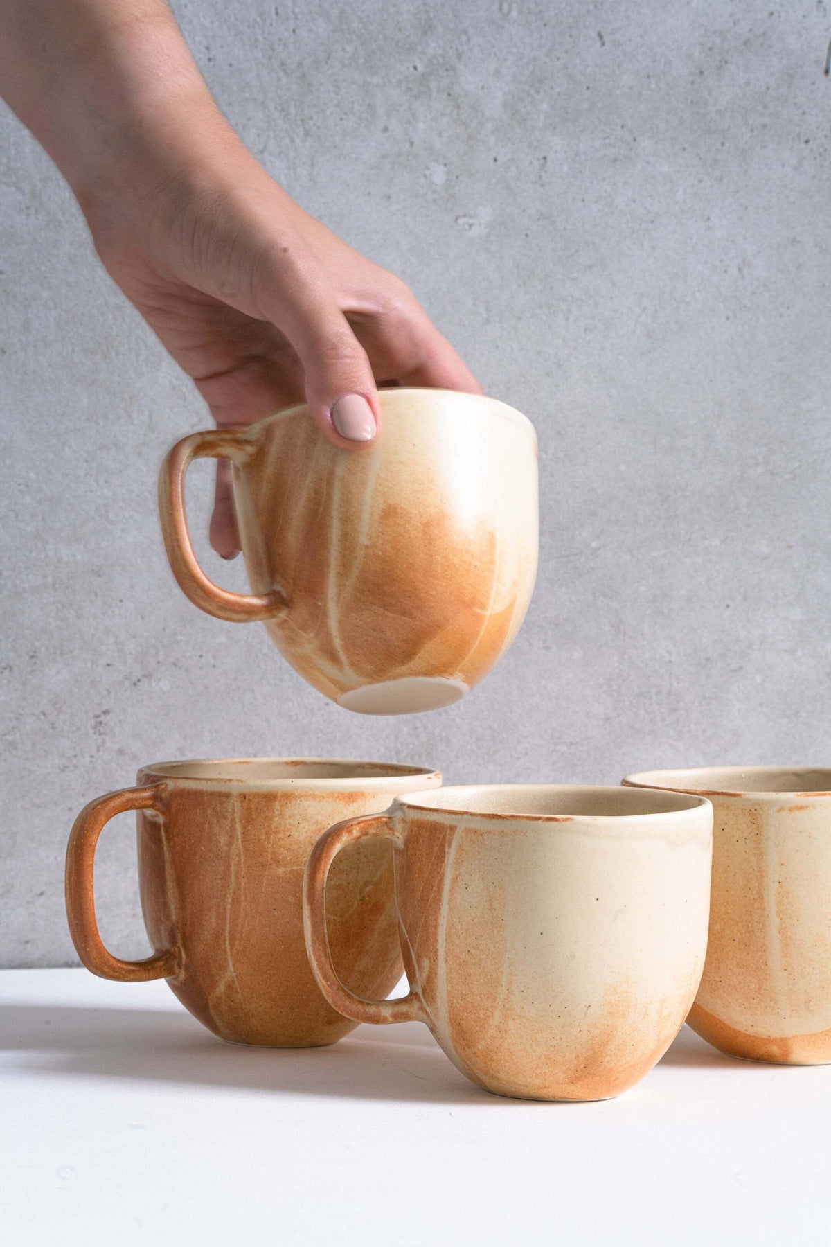 Stoneware beige coffee mugs by Creating Comfort, set of 5; hand lifted display on Tampa Home & Garden Store