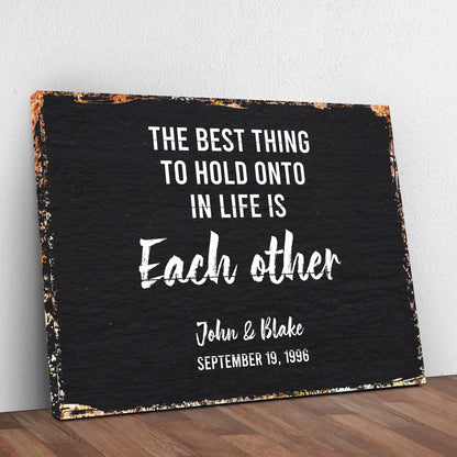 Canvas sign The Best Thing To Hold Onto Life Is Each Other, rustic black with white text and copper edges on Tampa Home & Garden Store