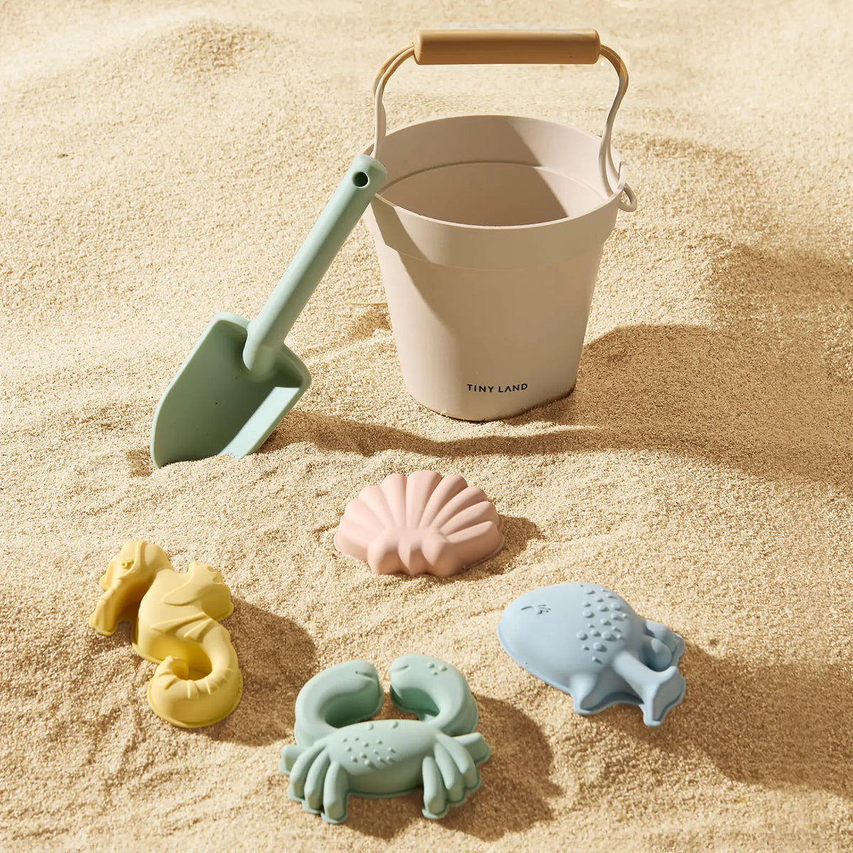 Tiny Land white bucket set with mint green shovel and pastel sea creature molds on sandy beach on Tampa Home & Garden Store