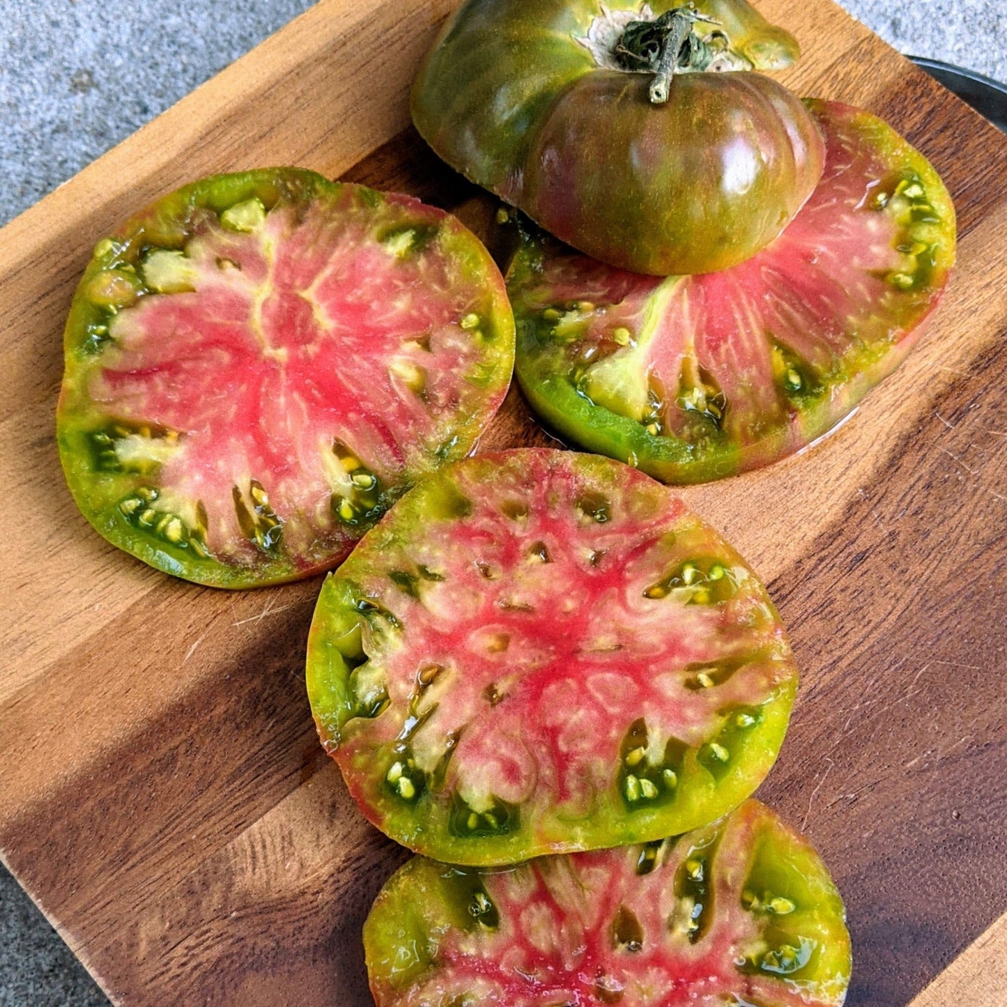 Ananas Noire tomato sliced open showing pink flesh and green rind with seeds on board on Tampa Home & Garden Store
