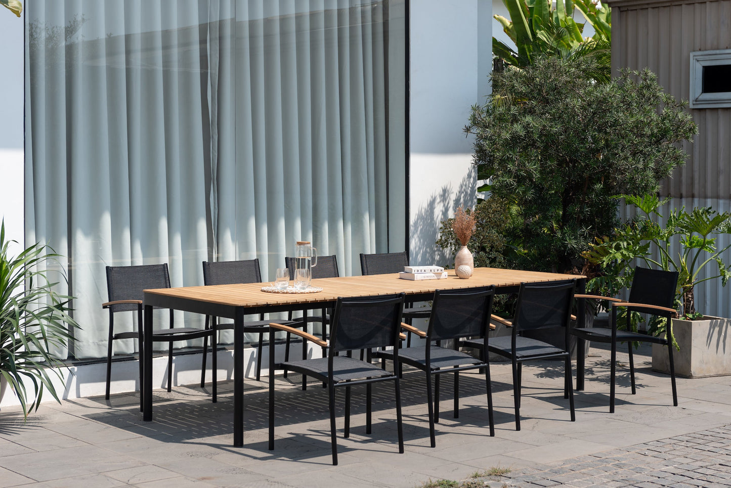 Topaz dark teak and aluminum extendable outdoor table with black legs and chairs on a patio on Tampa Home & Garden Store