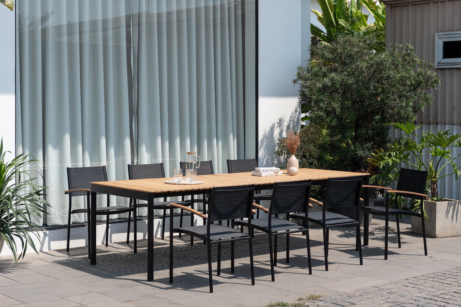Topaz dark teak and aluminum extendable outdoor table with black legs and chairs on a patio on Tampa Home & Garden Store