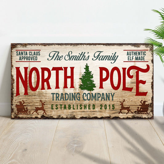 Canvas sign by Tailored Canvases, rustic wood look with red NORTH POLE text and green tree on Tampa Home & Garden Store