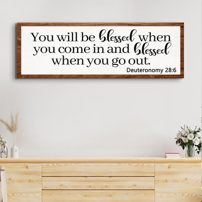 Canvas sign with black script on white panel in a wood frame displaying Deuteronomy 28:6 on Tampa Home & Garden Store