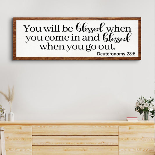 Canvas sign with black script on white panel in a wood frame displaying Deuteronomy 28:6 on Tampa Home & Garden Store