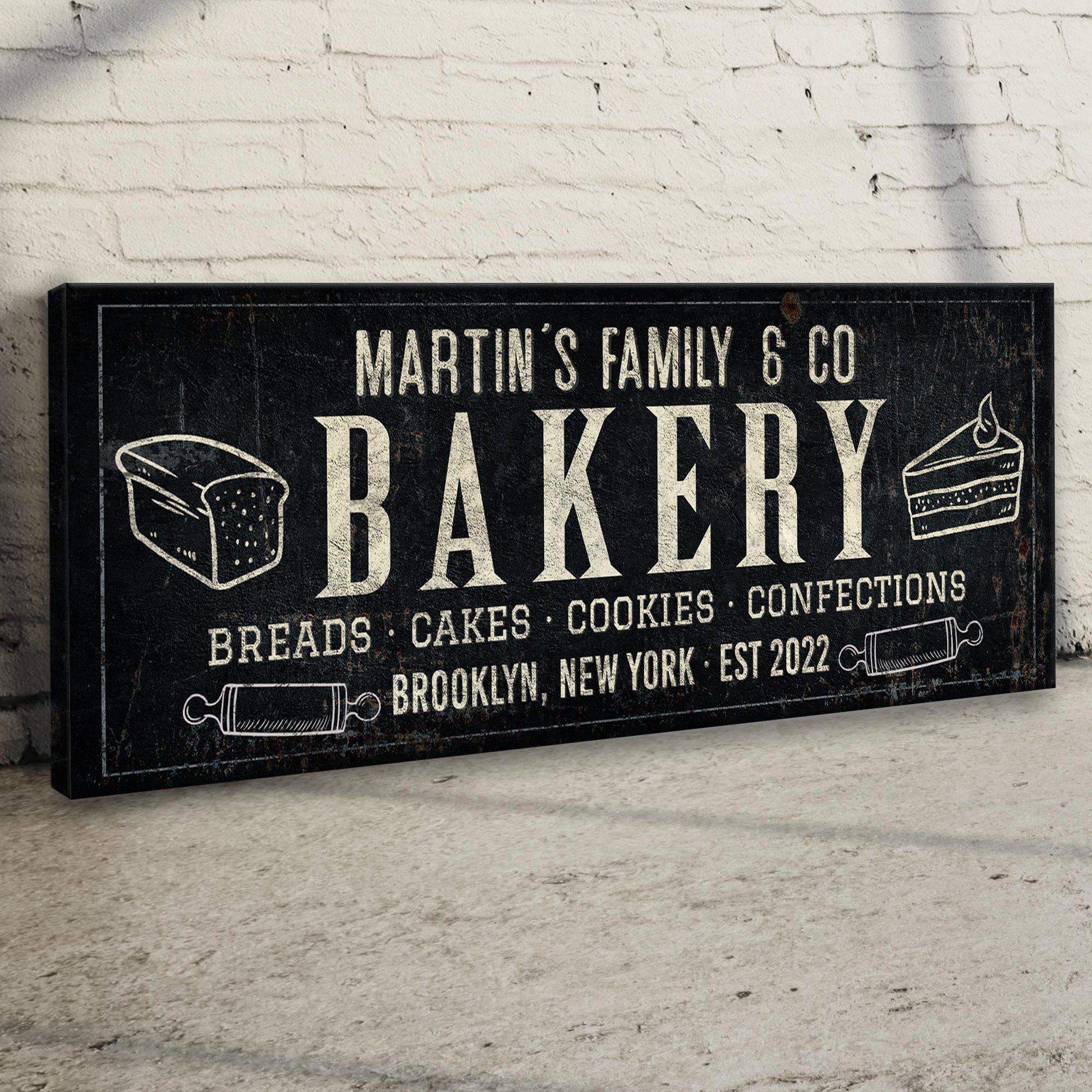 Bakery chalkboard canvas sign by Tailored Canvases with white text and cake slices on brick wall on Tampa Home & Garden Store