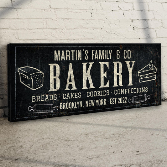 Bakery chalkboard canvas sign by Tailored Canvases with white text and cake slices on brick wall on Tampa Home & Garden Store