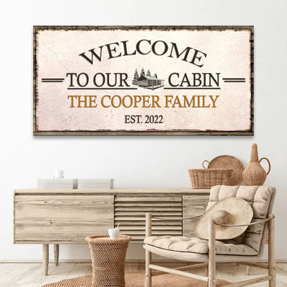 Welcome To Our Cabin canvas sign with cabin illustration and distressed beige backdrop on Tampa Home & Garden Store