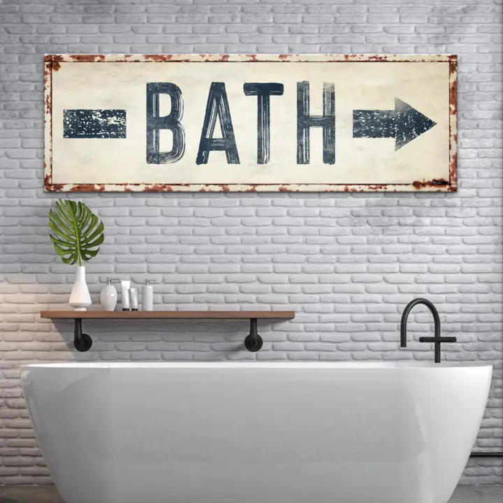 Bath Arrow Sign canvas wall art with a distressed rust frame on a brick bathroom wall on Tampa Home & Garden Store