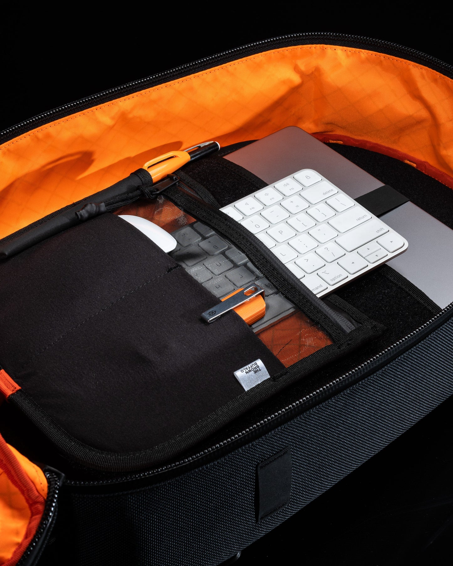 MOD 002 backpack by The Brown Buffalo with orange lining; holds white keyboard and laptop on Tampa Home & Garden Store